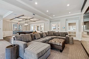 A large grey sectional sofa with a chaise lounge and ottoman in a spacious living room.
